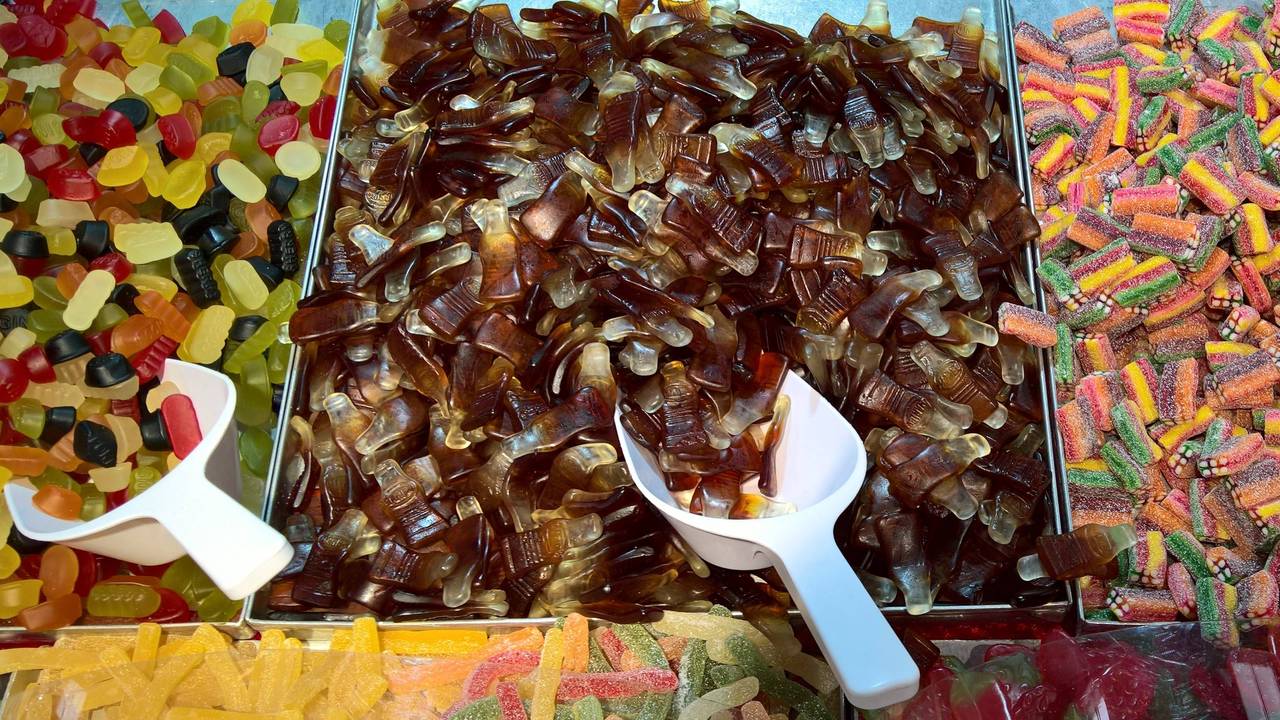 Bunter Süßigkeitenstand mit Gummibonbons, sauren Streifen und vielen braunen Colaflaschen-Gummis