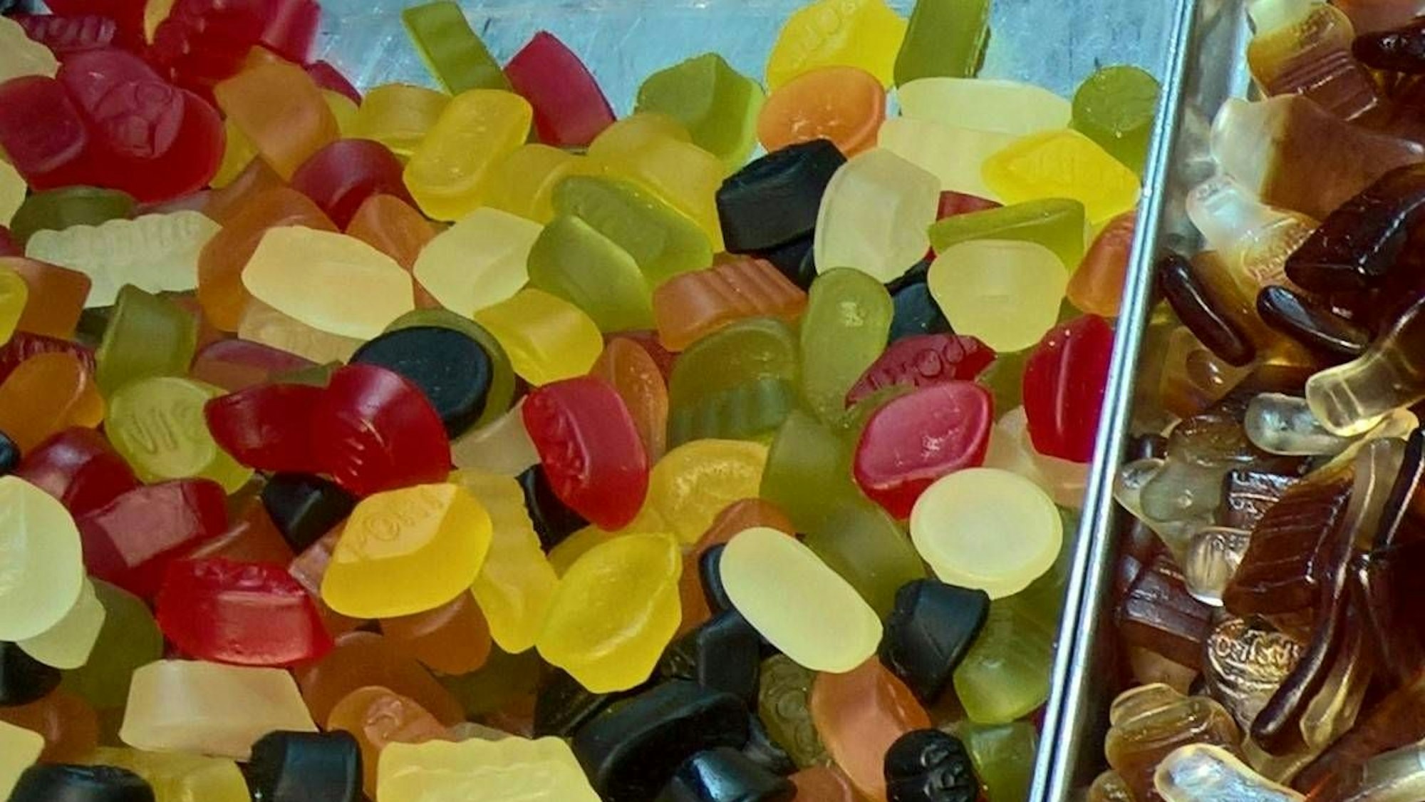 Bunter Süßigkeitenstand mit Gummibonbons, sauren Streifen und vielen braunen Colaflaschen-Gummis