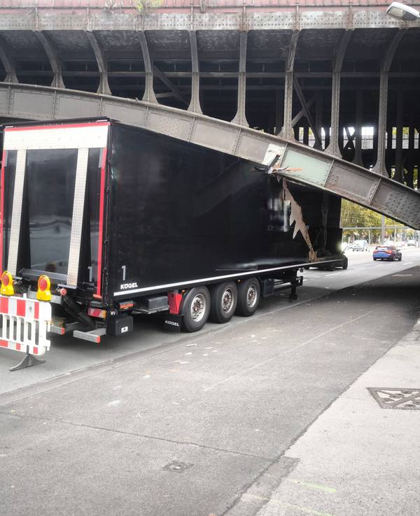 Ein Lkw klemmt unter einer Brücke, sein Auflieger ist eingedrückt.