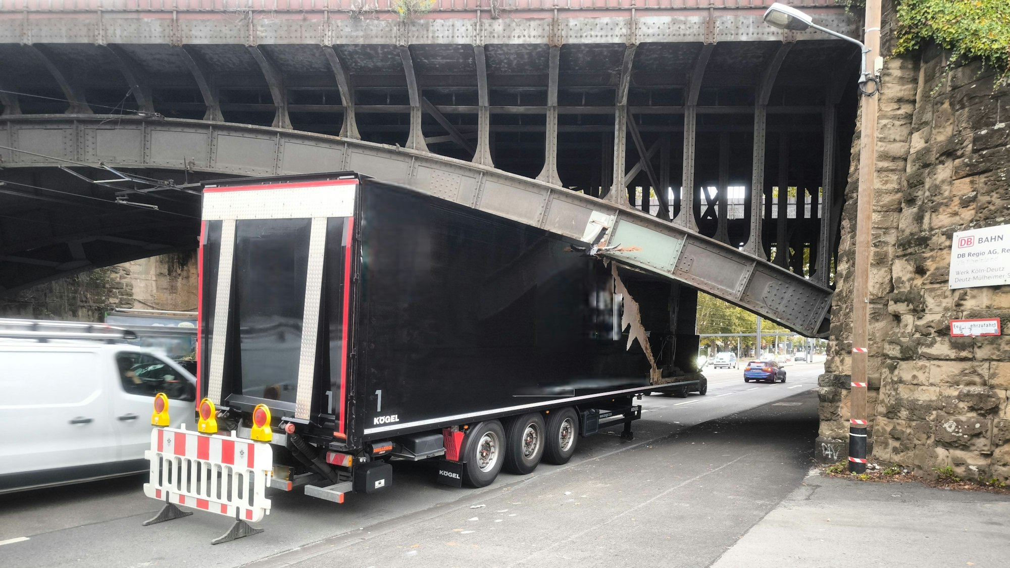 Ein Lkw-Aufhänger klemmt unter einer Brücke fest, der Auflieger ist stark eingedrückt.