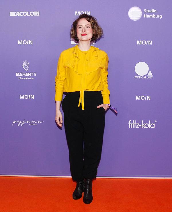 Wanda Perdelwitz in gelber Bluse und schwarzer Hose vor Sponsorenwand