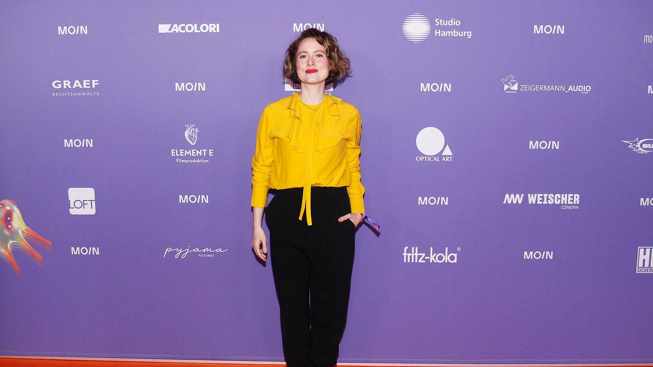Wanda Perdelwitz in gelber Bluse und schwarzer Hose vor Sponsorenwand