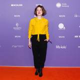 Wanda Perdelwitz in gelber Bluse und schwarzer Hose vor Sponsorenwand