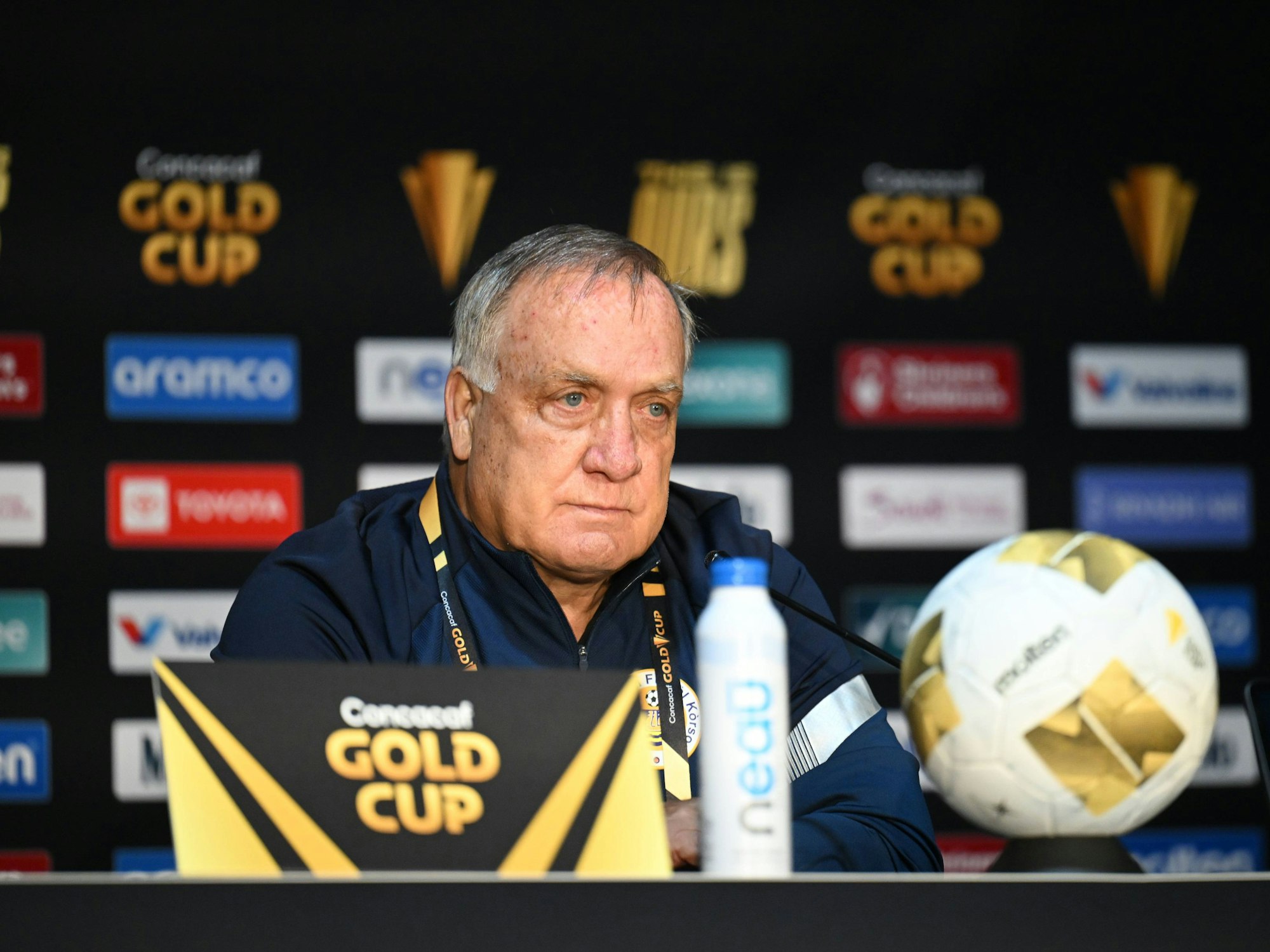 Dick Advocaat sitzt auf einer Pressekonferenz und hört einer Frage zu.