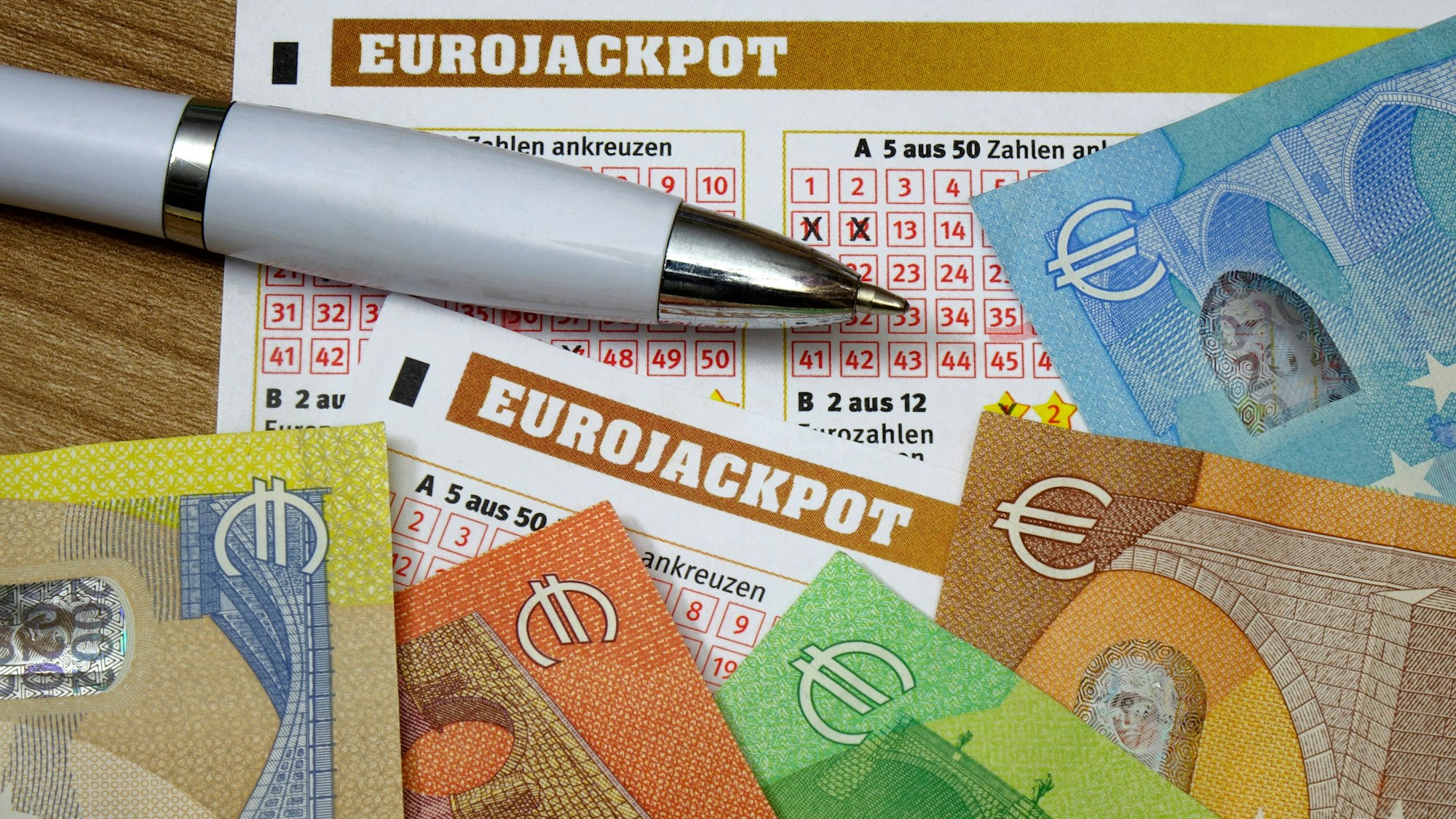 Eurojackpot-Lottoschein mit Kugelschreiber und bunten Euro-Banknoten