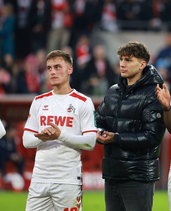 Julian Pauli und Elias Bakatukanda klatschen in die Hände. Pauli trägt eine schwarze Winterjacke, Bakatukanda das Trikot des 1. FC Köln.