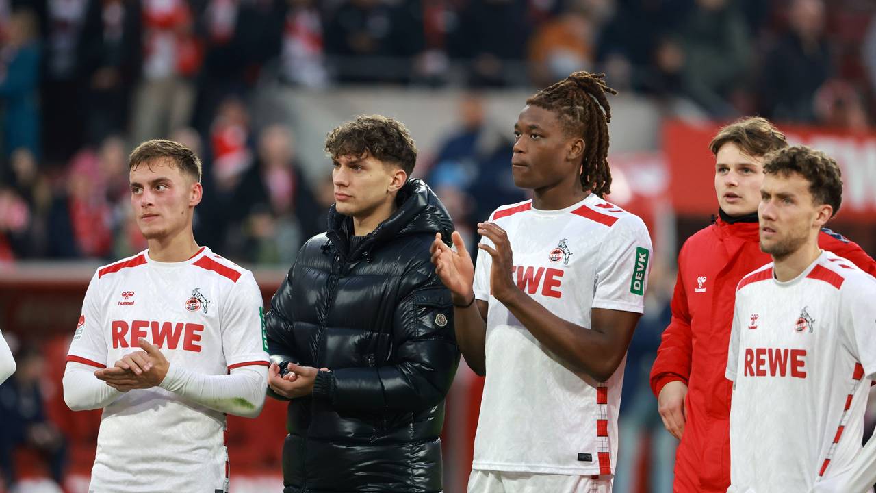 Julian Pauli und Elias Bakatukanda klatschen in die Hände. Pauli trägt eine schwarze Winterjacke, Bakatukanda das Trikot des 1. FC Köln.