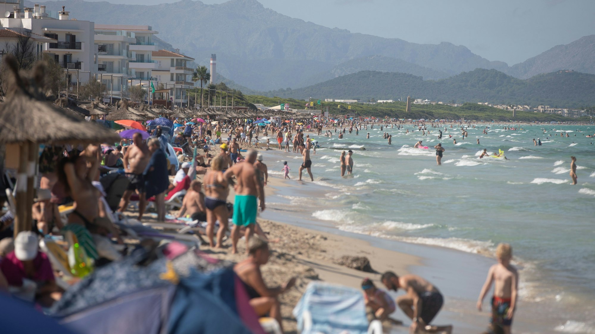 Menschen schwimmen und sonnen sich am Strand von Mallorca.