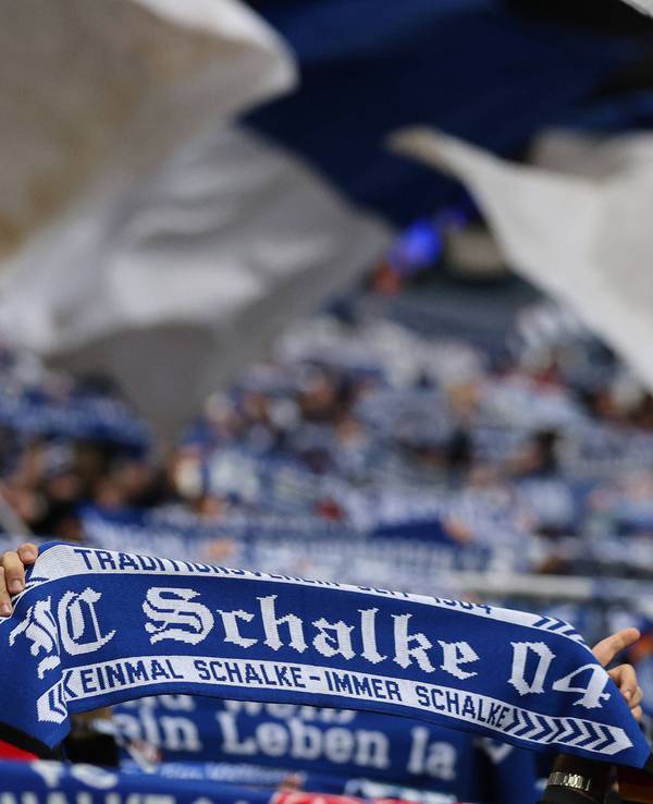 Schalke-Fans halten ihre Schals in die Höhe.