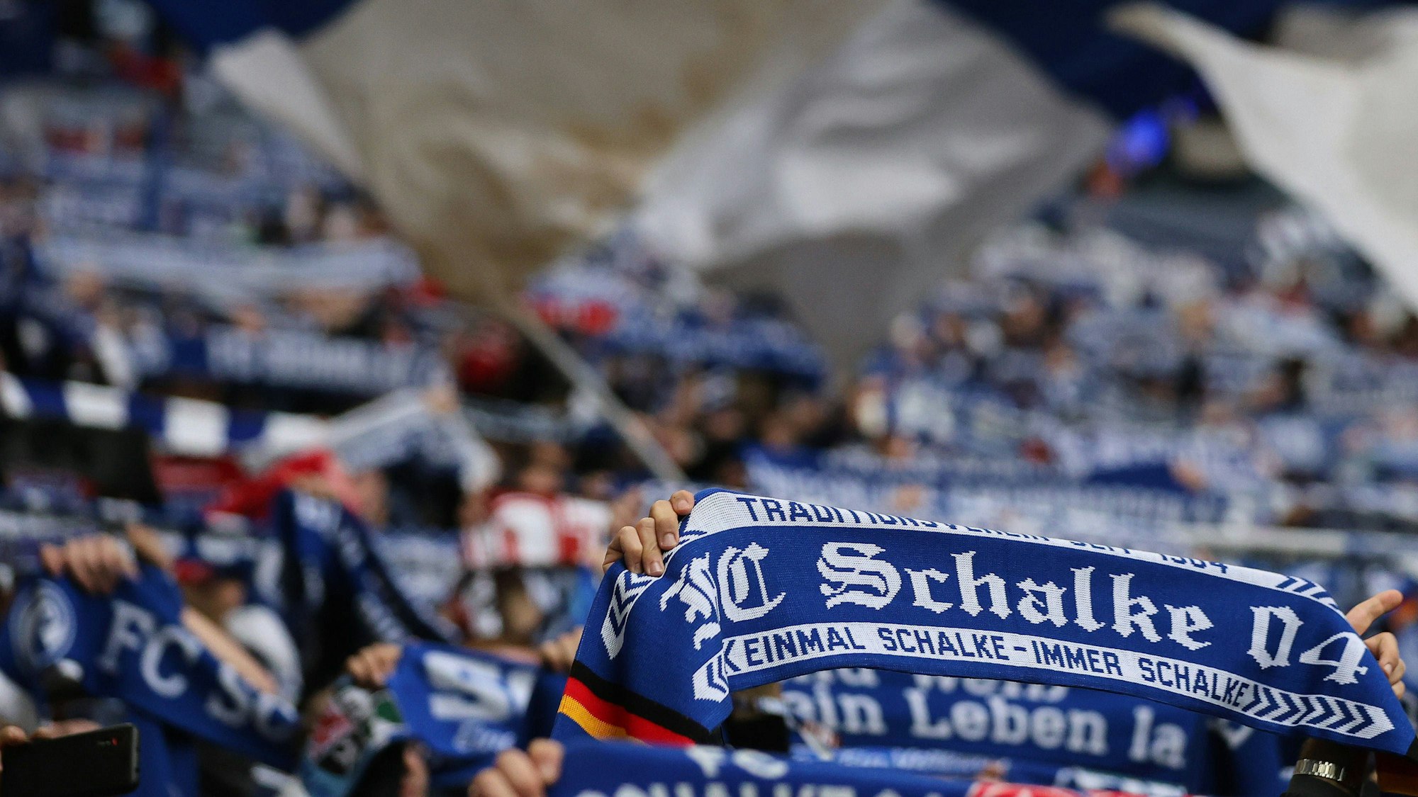 Schalke-Fans halten ihre Schals in die Höhe.