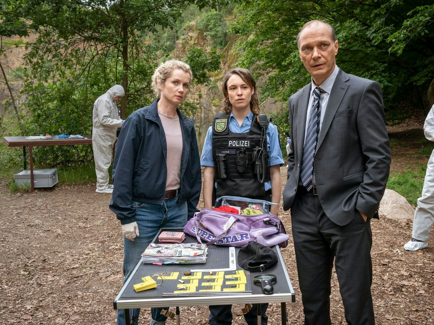 Diese Dinge trug das tote Mädchen bei sich: Leonie Winkler (Cornelia Gröschel, links), Polizistin Antje (Victoria Schulz) und Peter Schnabel (Martin Brambach) untersuchen die Tasche von Lilly-Marie. (Bild: MDR/MadeFor Film/Steffen Junghans)