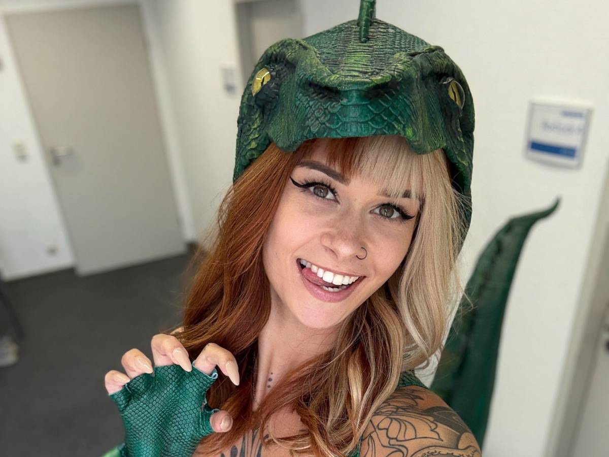 SallyDinosaur macht ein Selfie in einem Dinosaurierkostüm.