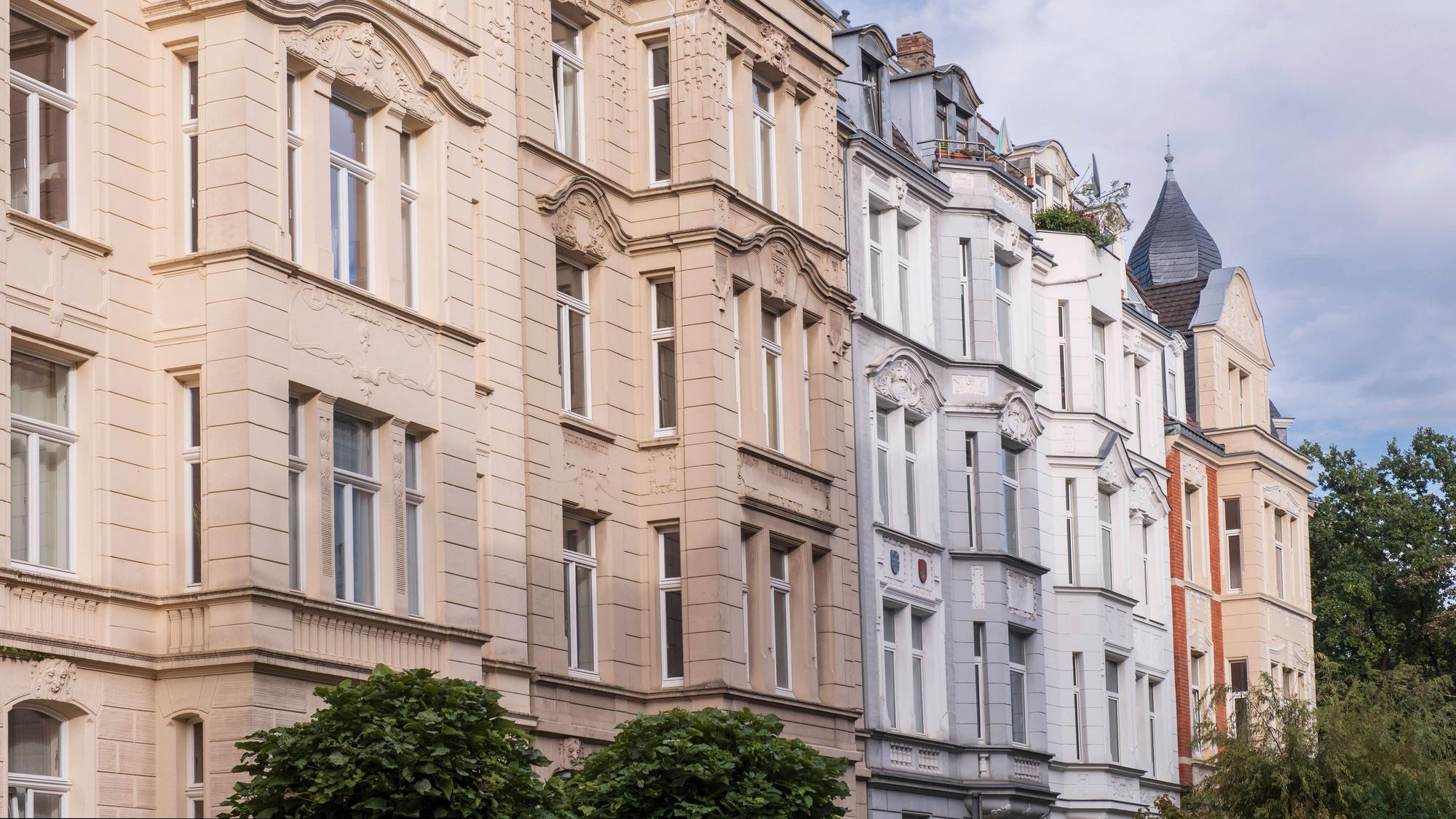 Reihe stilvoller Altbau-Mietshäuser mit detailreichen Fassaden unter leicht bewölktem Himmel