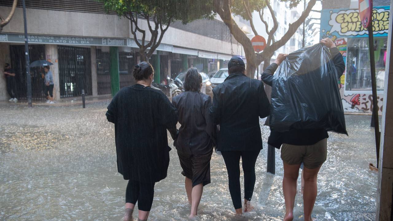 Menschen gehen eine überflutete Straße auf Ibiza entlang. Heftige Regenfälle haben zahlreiche Straßen der Mittelmeerregion Spaniens in reißende Flüsse verwandelt.
