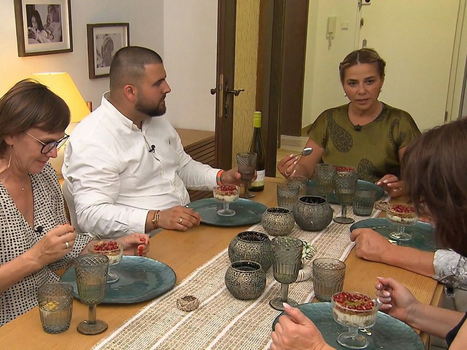 Mehrere Personen sitzen um einen Tisch, vor sich Dessertschälchen.