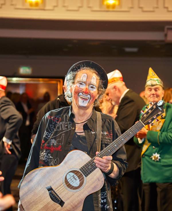 Peter Horn kommt mit Gitarre in einen Saal.