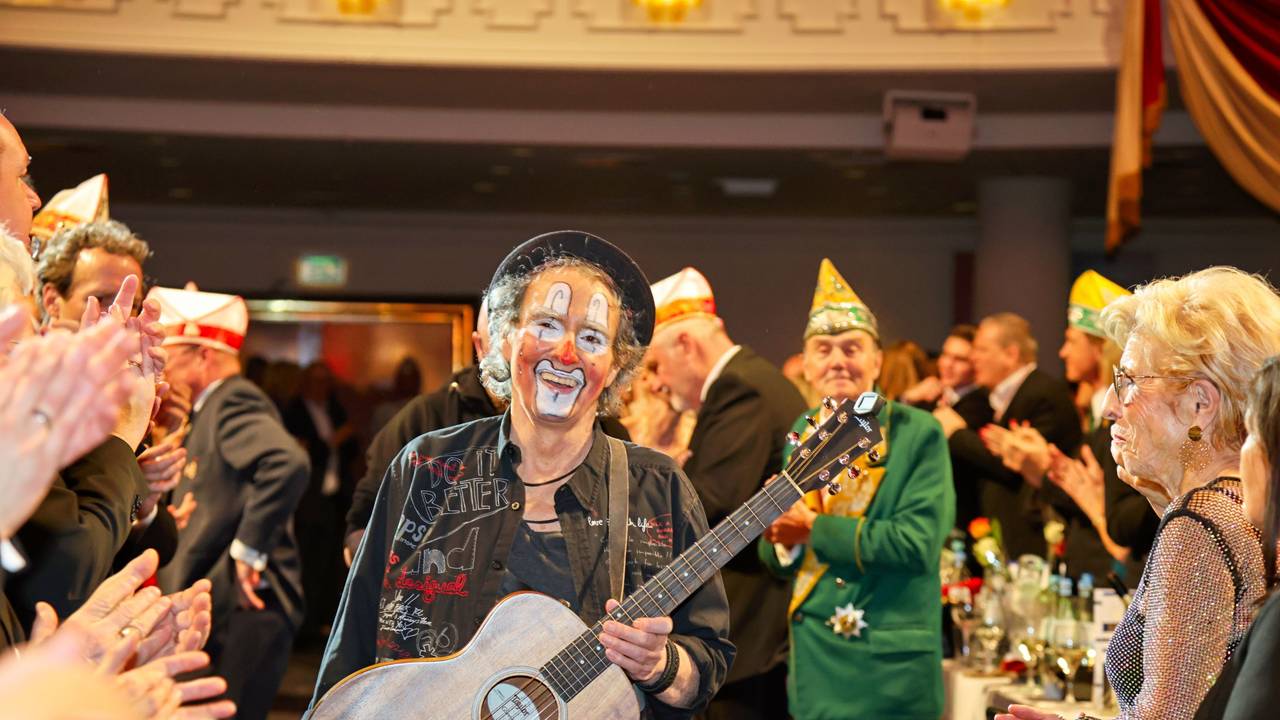 Peter Horn kommt mit Gitarre in einen Saal.