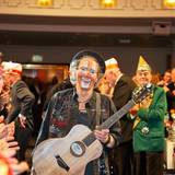 Peter Horn kommt mit Gitarre in einen Saal.
