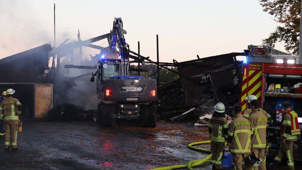 Einsatzkräfte von Feuerwehr und THW arbeiten an einer Lagerhalle mit Oldtimern, die in Brand geraten war. Die Feuerwehr brachte den Brand nach eigenen Angaben unter Kontrolle, war aber auch am frühen Morgen noch am Einsatzort.