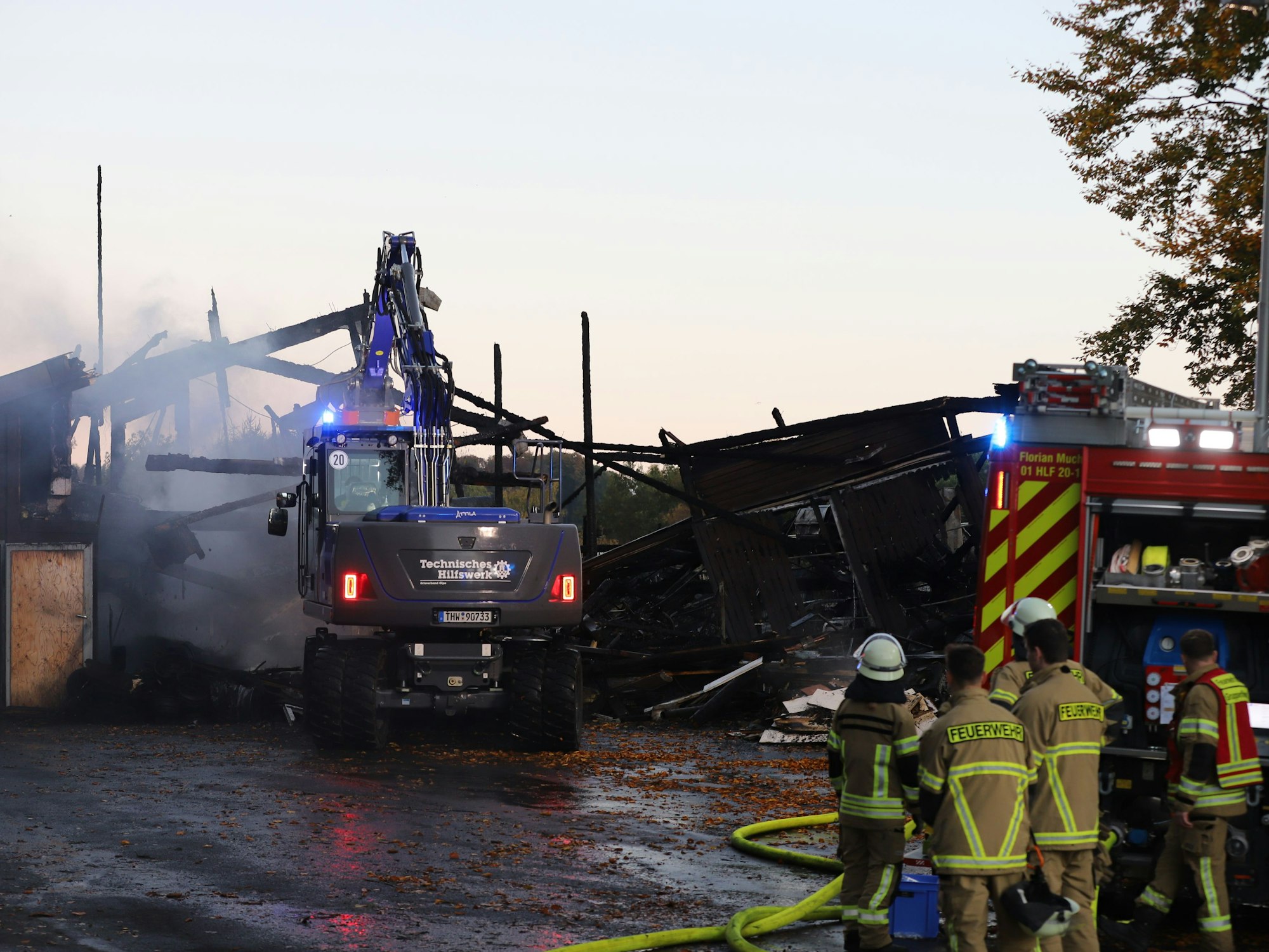 Einsatzkräfte von Feuerwehr und THW arbeiten an einer Lagerhalle mit Oldtimern, die in Brand geraten war. Die Feuerwehr brachte den Brand nach eigenen Angaben unter Kontrolle, war aber auch am frühen Morgen noch am Einsatzort.