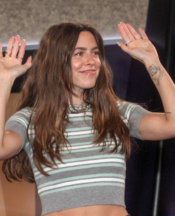 Vanessa Mai lächelt mit erhobenen Händen in einem gestreiften Crop-Top.