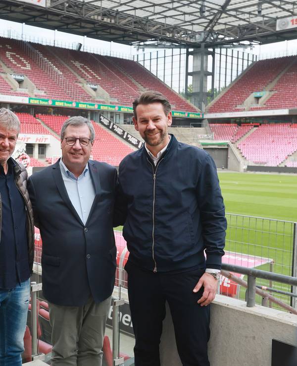 Friedhelm Funkel, Werner Wolf, Thomas Kessler stehen Arm in Arm auf der Tribüne des Stadions und posieren für ein Foto.