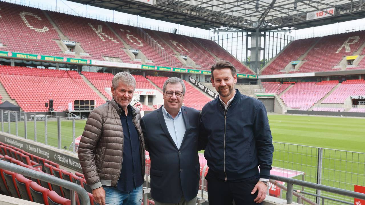 Friedhelm Funkel, Werner Wolf, Thomas Kessler stehen Arm in Arm auf der Tribüne des Stadions und posieren für ein Foto.