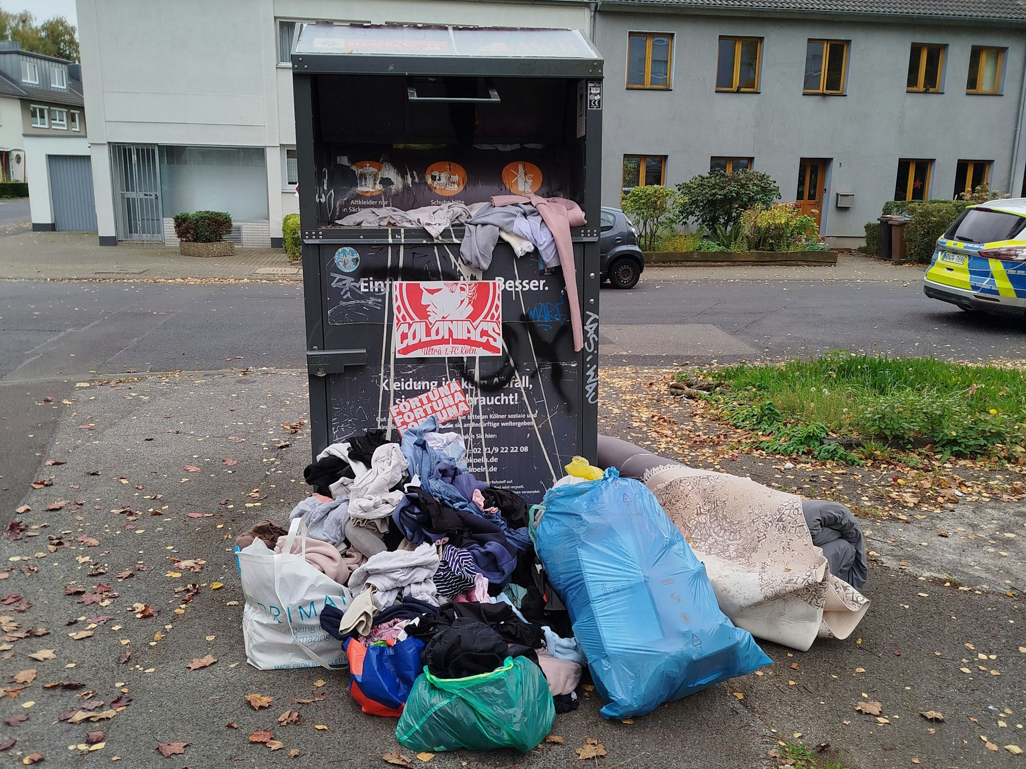 Müllsäcke stehen vor einem Altkleidercontainer.