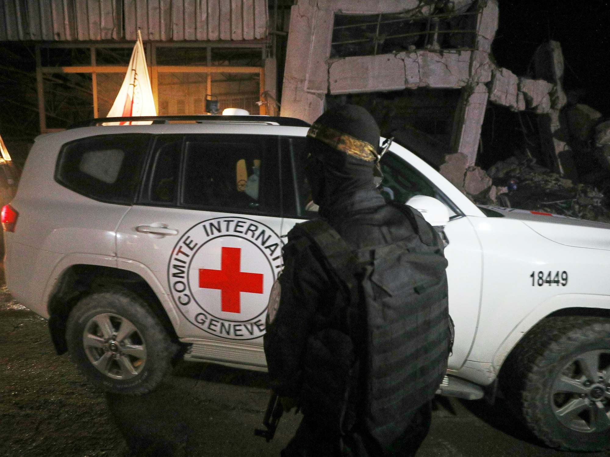 Ein bewaffneter Mann in der Uniform der al-Qassam-Brigaden, dem militärischen Flügel der Hamas, steht Wache, als Fahrzeuge des Roten Kreuzes ein Lagerhaus verlassen.