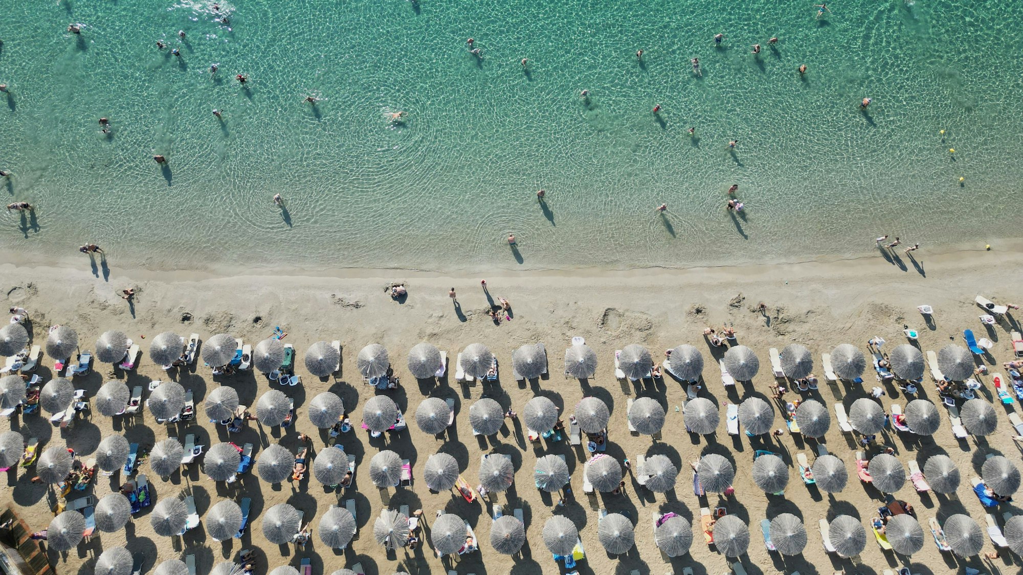 Menschen genießen das Meer an einem Strand in Griechenland.