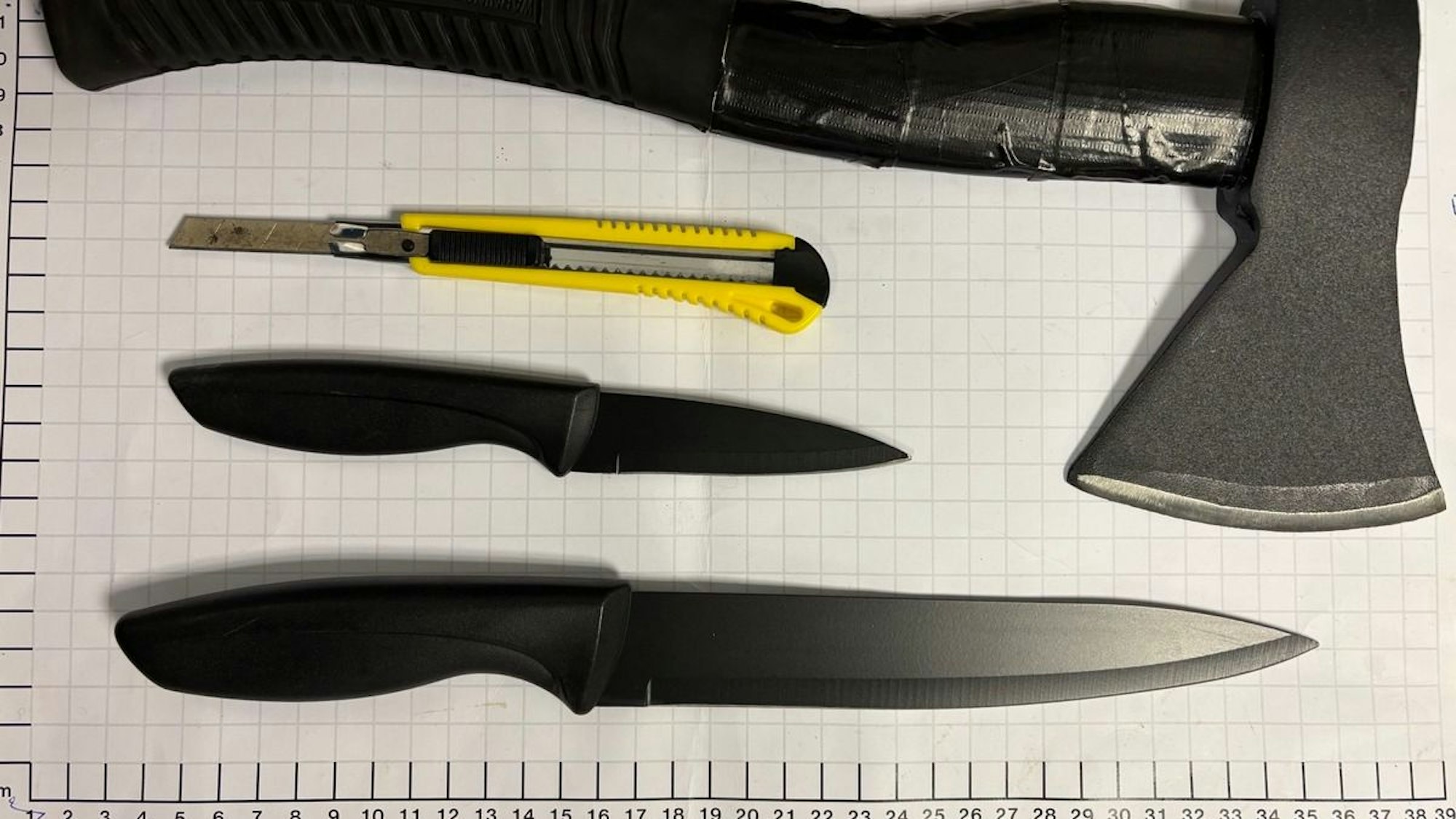 Eine Axt, mehrere Messer und Pfeffersprays liegen auf einem Tisch.
