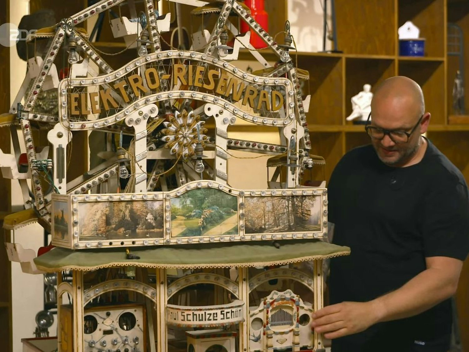 Ein Mann steht neben einem Miniatur-Riesenrad.
