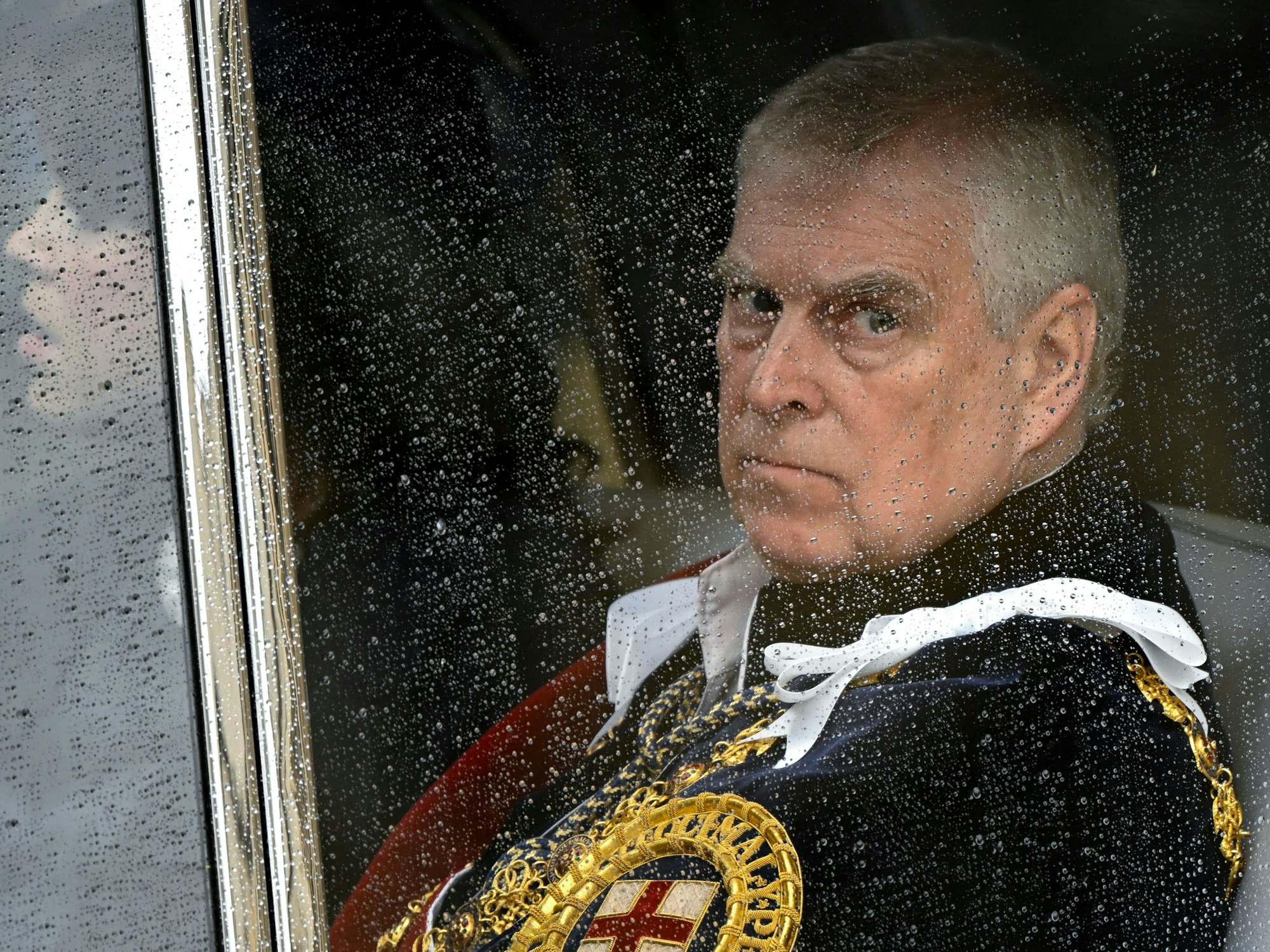 Prinz Andrew guckt durch ein regennasses Fenster.