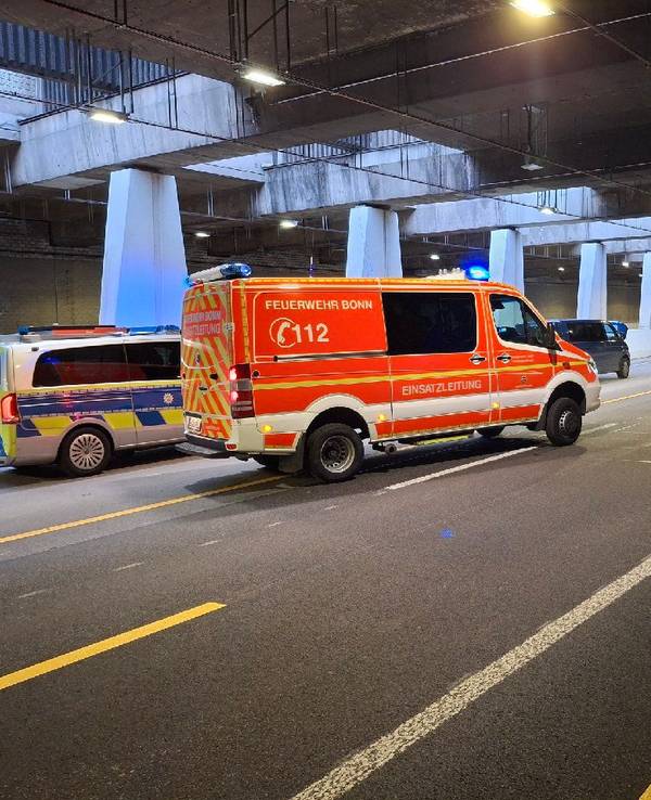 Ein Streifenwagen und ein Feuerwehrfahrzeug stehen in einem Tunnel, davor halb verdeckt ein Kleinbus.