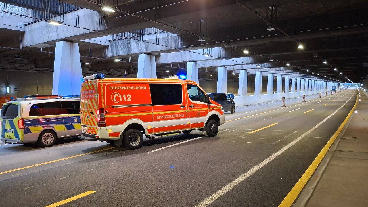 Ein Streifenwagen und ein Feuerwehrfahrzeug stehen in einem Tunnel, davor halb verdeckt ein Kleinbus.