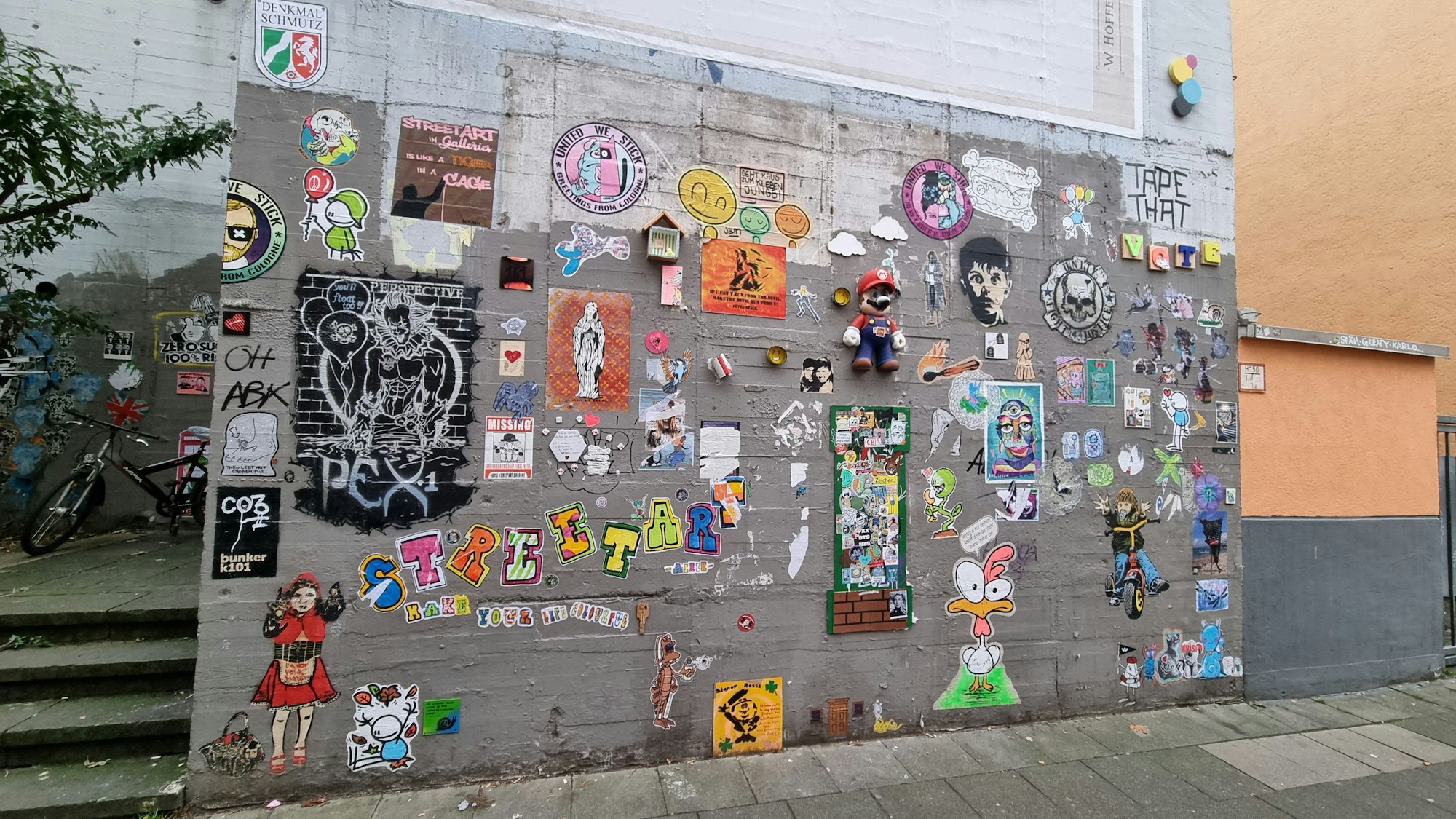 An einer Wand hängen Plakate und eine Figur von „Super Mario“.