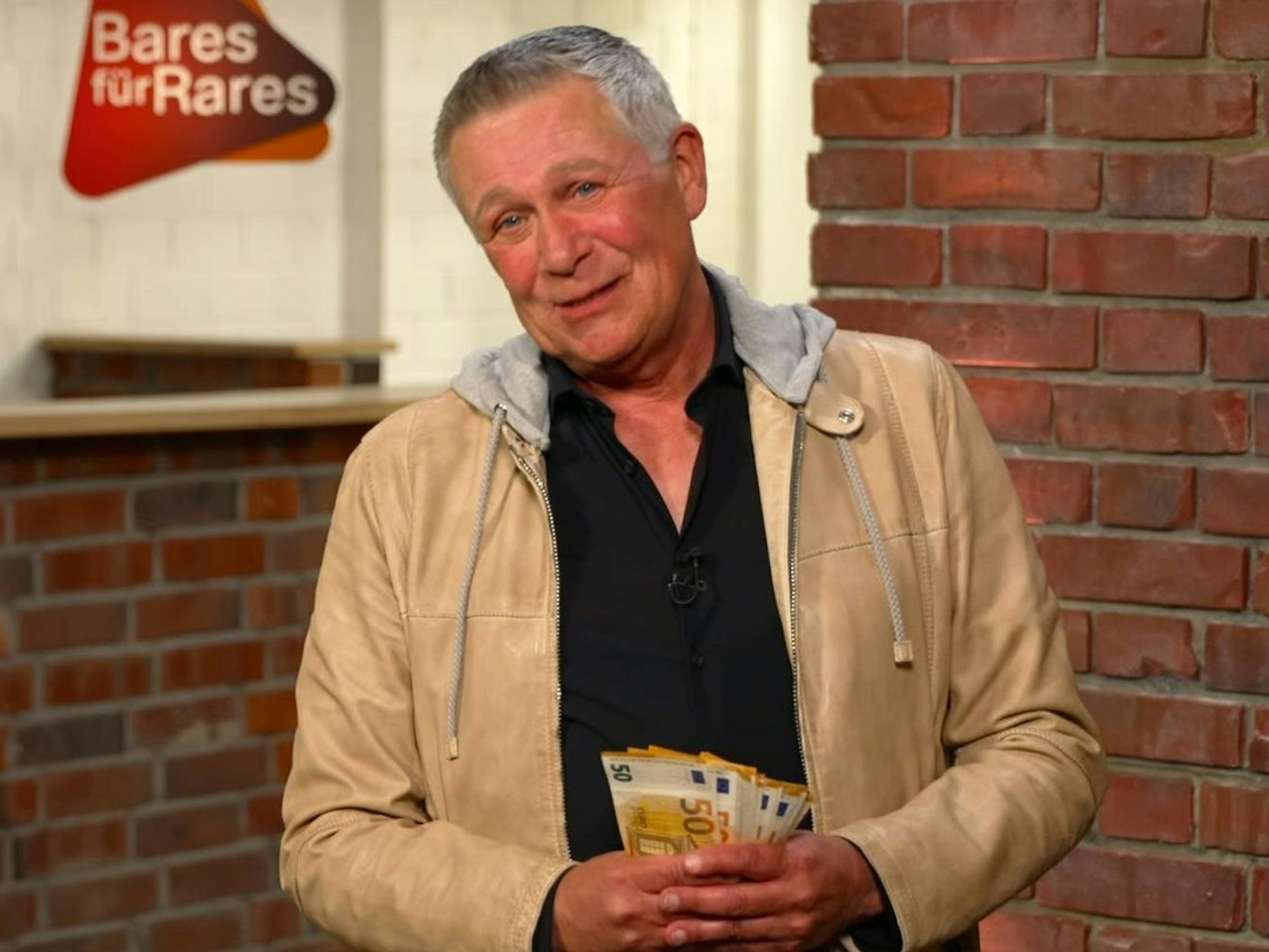 Ein Mann hält mehrere 50-Euro-Scheine gefächert in der Hand.