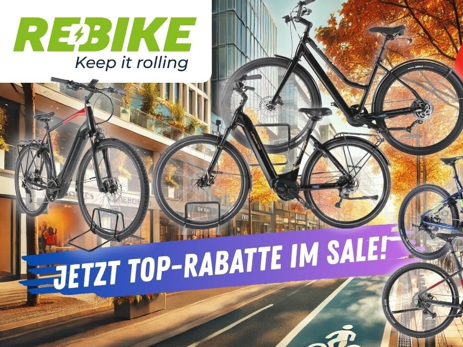 E-Mountain-Bikes, Trekking Bikes und City-E-Bikes vor einer herbstlichen Innenstadt-Kulisse. Mehrere bekannte E-Bike Marken und Hersteller sind vertreten.