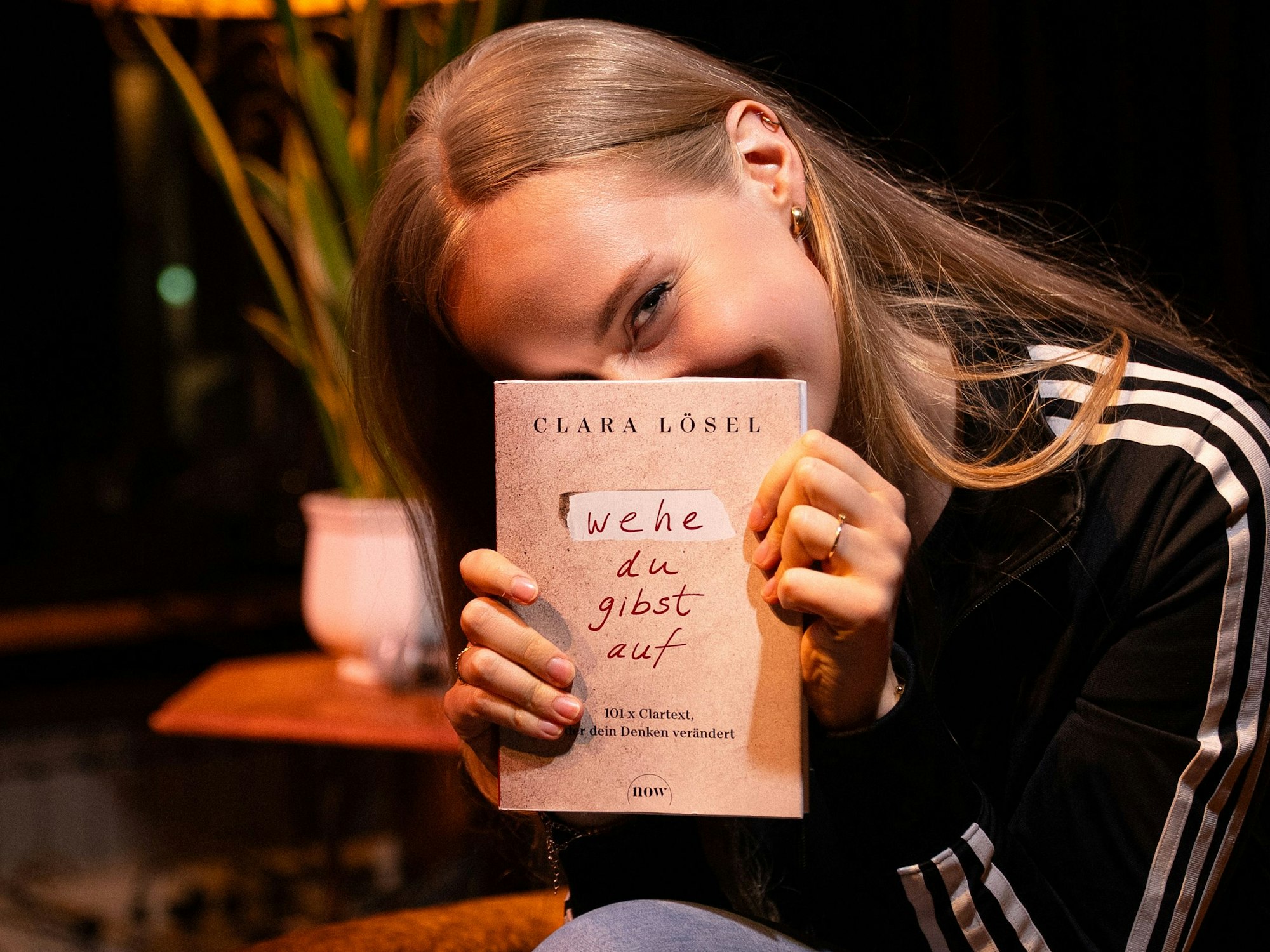Die Autorin Clara Lösel hält ihr Buch in die Kamera.