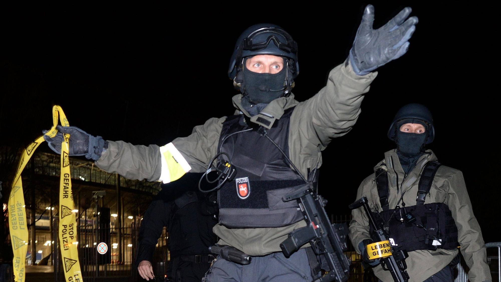 Polizisten mit Sturmgewehren stehen vor dem geschlossenen Stadion und sperren den Bereich ab.