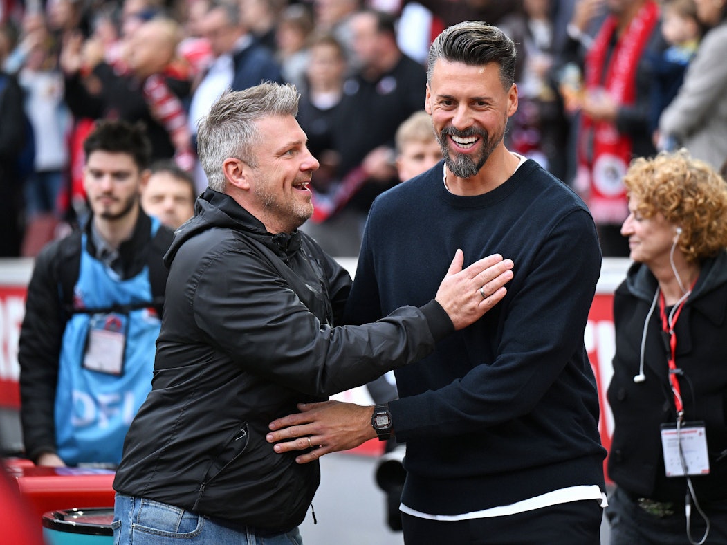 Lukas Kwasniok (1. FC Köln) und Sando Wagner (FC Augsburg) haben beim Spiel am 18. Oktober 2025 Spaß.