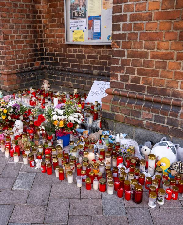 Vor einer Kirche stehen unzählige Grablichter, Blumen und Plüschtiere im Gedenken an den vermissten achtjährigen Fabian, auf einem Schild steht "In Trauer um Fabian".