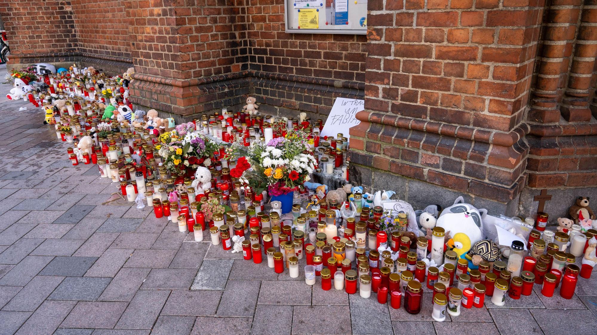 Vor einer Kirche stehen unzählige Grablichter, Blumen und Plüschtiere im Gedenken an den vermissten achtjährigen Fabian, auf einem Schild steht "In Trauer um Fabian".