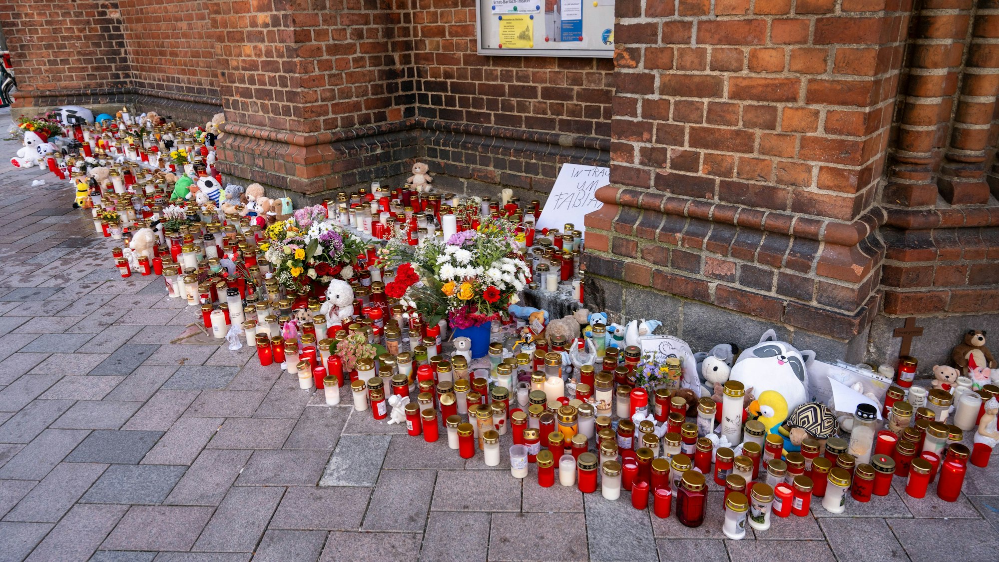 Vor einer Kirche stehen unzählige Grablichter, Blumen und Plüschtiere im Gedenken an den vermissten achtjährigen Fabian, auf einem Schild steht "In Trauer um Fabian".