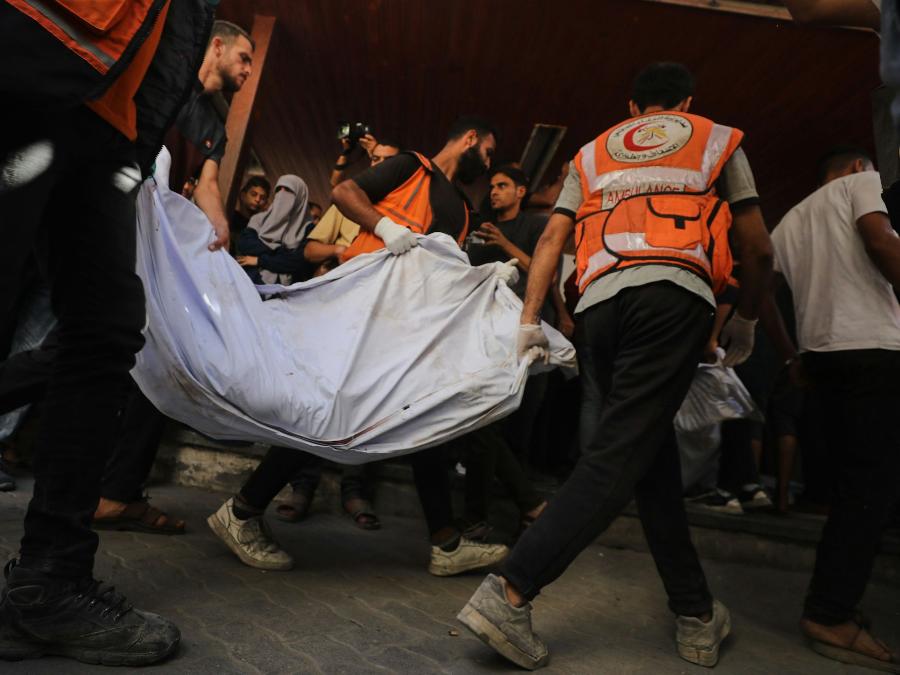 Menschen tragen einen Leichnam in einem Tuch weg.