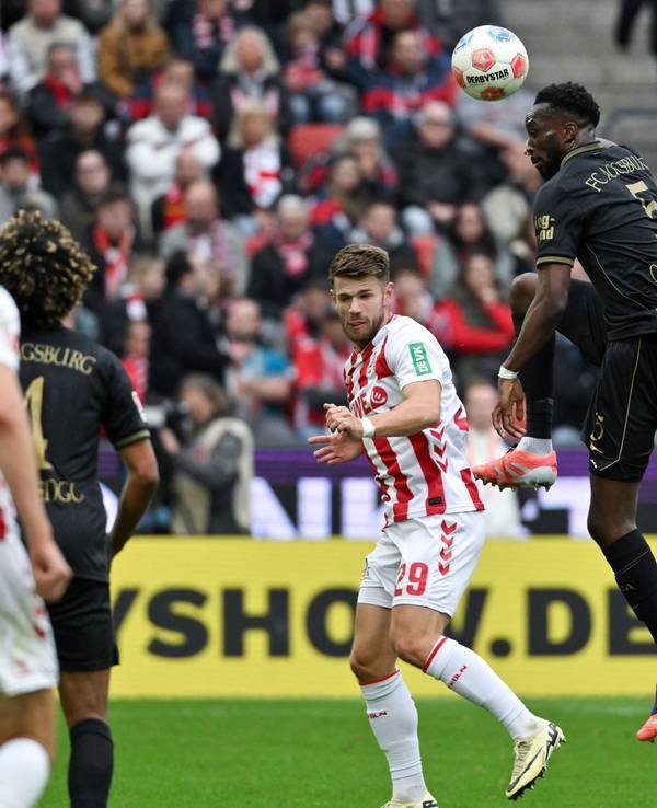 Chrislain Matsima (FC Augsburg) köpft den Ball vor Jan Thielmann (1. FC Köln) weg.