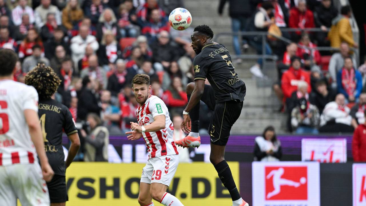 Chrislain Matsima (FC Augsburg) köpft den Ball vor Jan Thielmann (1. FC Köln) weg.
