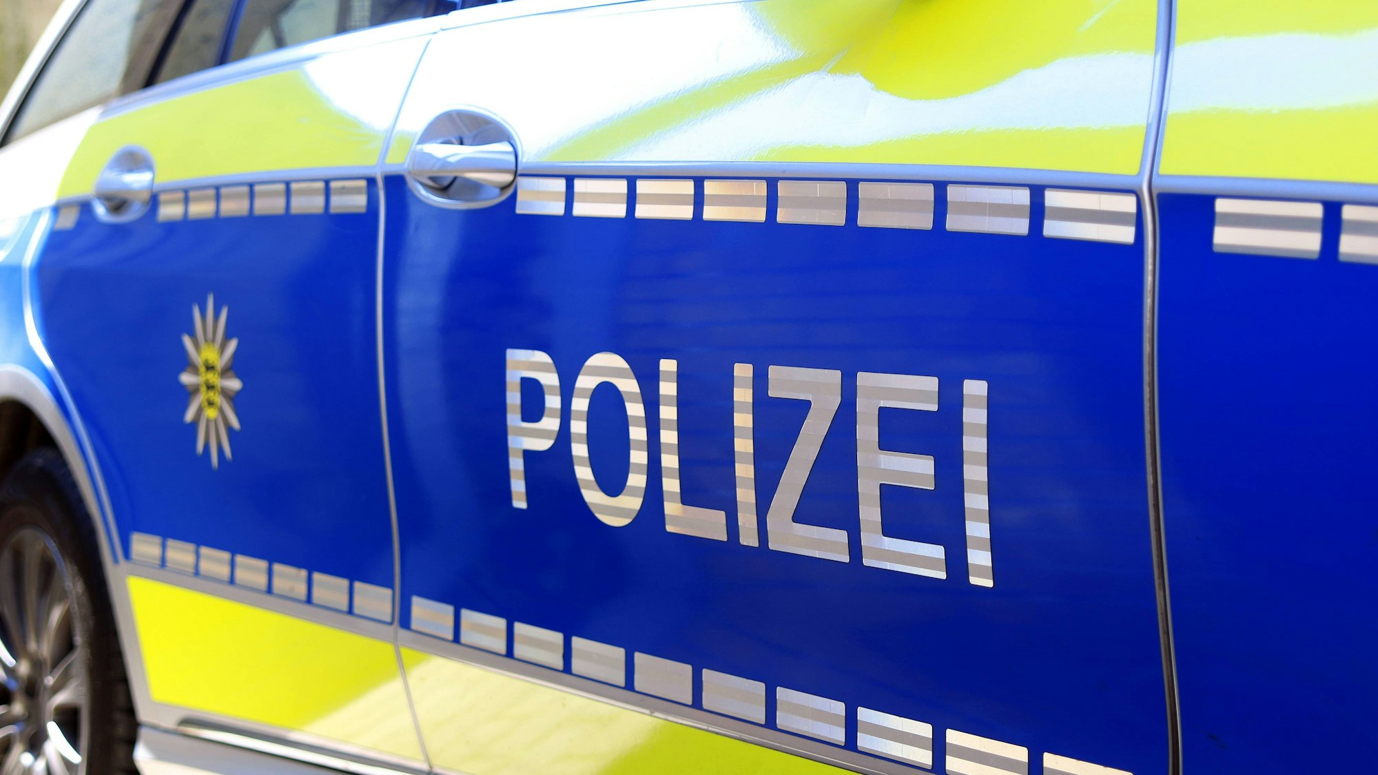 Symbolbild: Nahaufnahme eines deutschen Polizeiautos mit „POLIZEI“-Schriftzug und Emblem seitlich.