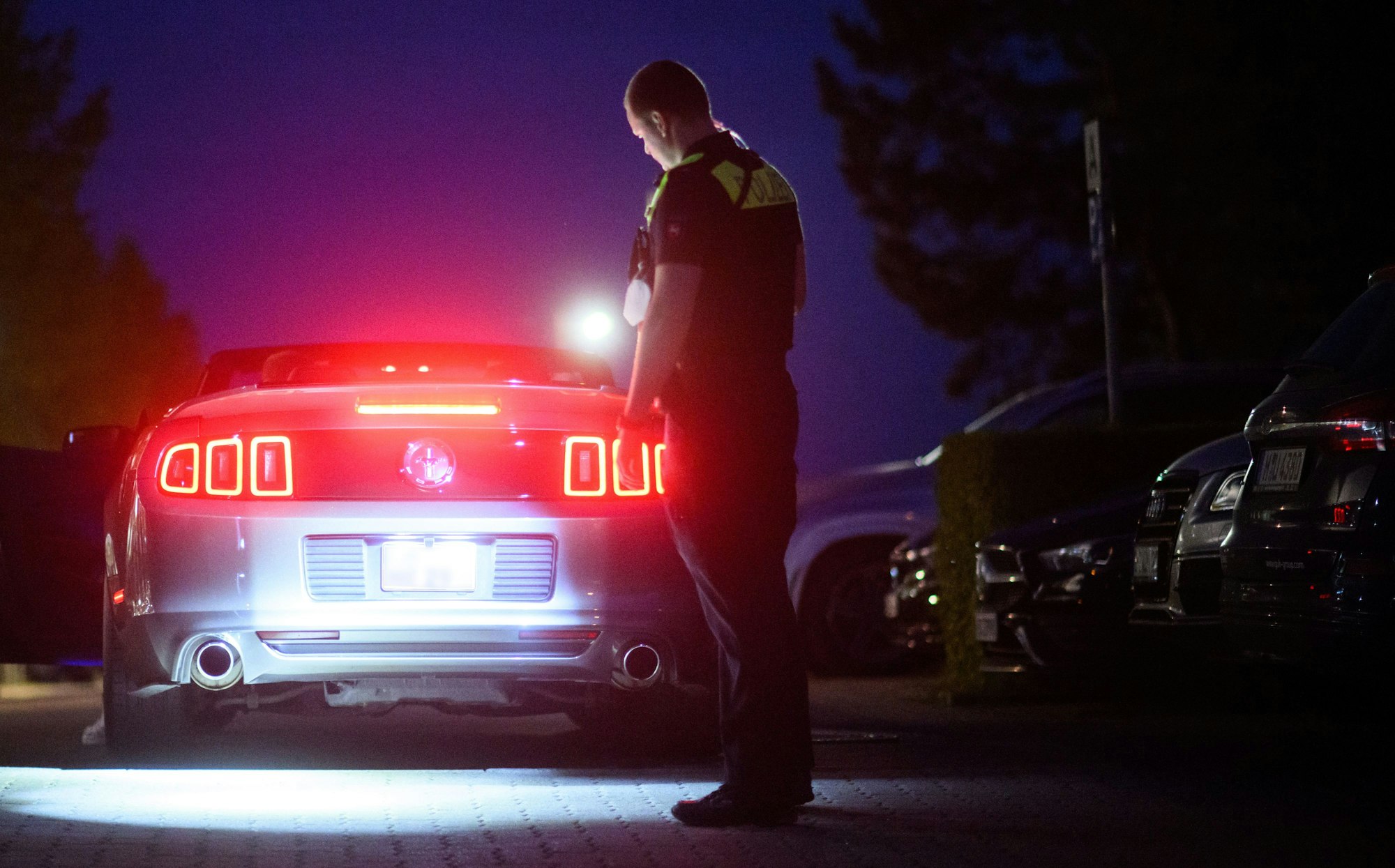 Polizisten kontrollieren in der Dunkelheit mit Taschenlampe ein getuntes Fahrzeug.
