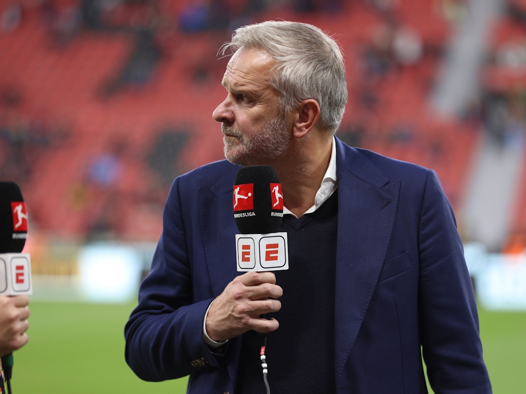 Didi Hamann steht mit Mikrofon am Spielfeldrand.